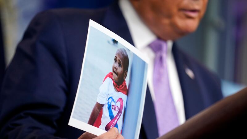 FILE - Then-President Donald Trump holds a photo of LeGend Taliferro as he speaks at a news...