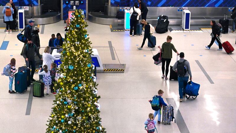 A family passes a Christmas tree while checking their bags for a flight at Logan International...
