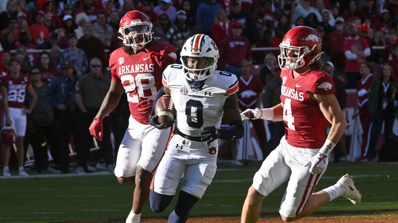 Auburn wide receiver Koy Moore (0) slips past Arkansas defenders Jaheim Thomas (28) and Malik...